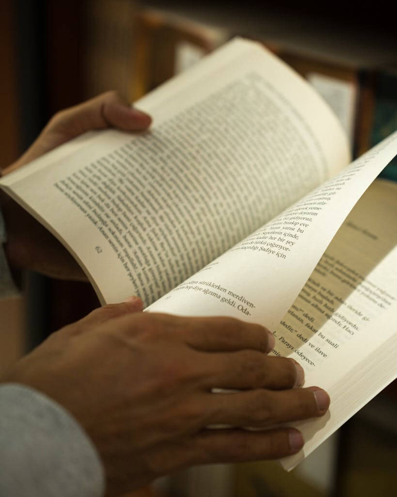 Close-up of hands flipping pages of a book in a library in Ankara, Türkiye.